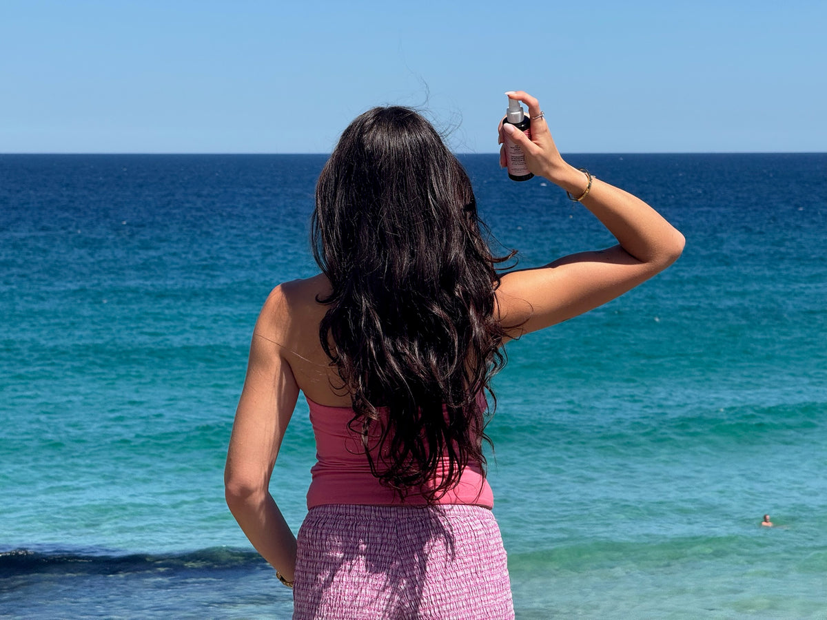 Woman taking a photo of the ocean with a clear blue sky