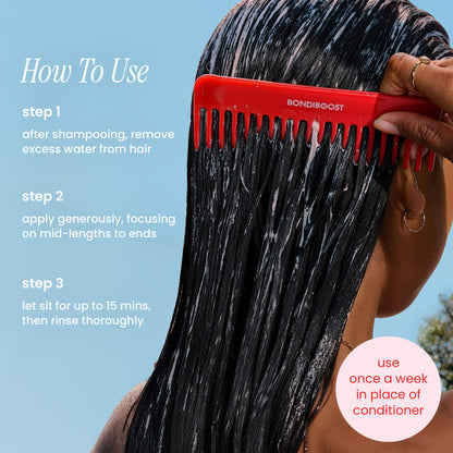 Person applying hair product with a red comb against a blue sky background
