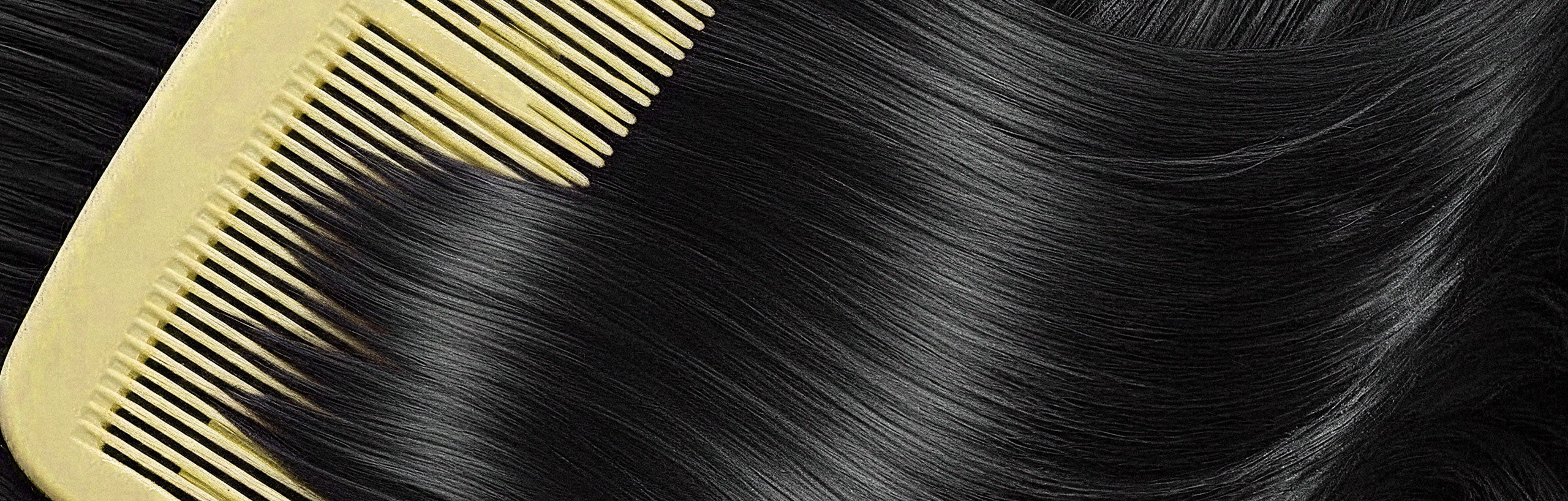 Close-up of a comb through straight black hair